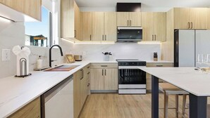 Una cucina moderna con mobili in legno, forno a incasso e zona pranzo con tavolo e sedie.