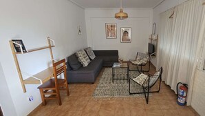 Un salon comprenant un canapé, deux fauteuils, une petite table, un luminaire suspendu et un extincteur.