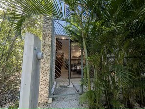 A modern building with a stone facade, a metal gate, and a palm tree in the foreground. - Private Pool + Rooftop / Stylish Tulum House for 6 (Tulum)