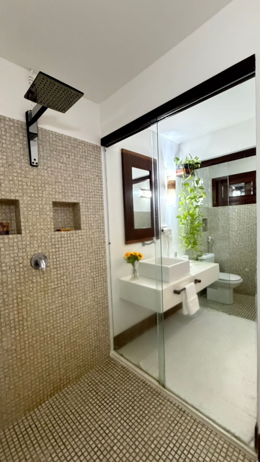 Een moderne badkamer met een douchecabine van glas, een witte wastafel en een spiegel.