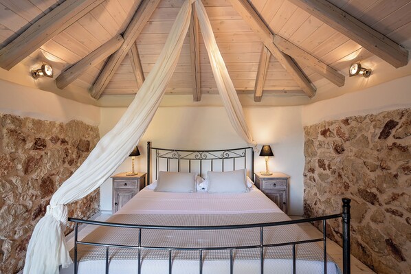 Ein Schlafzimmer mit Steinwand, einem Baldachinbett und zwei Nachttischlampen.