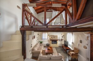 Ein großzügiger Wohnbereich mit hohen Decken, Kamin, einer Couch, einem Couchtisch und einem Fernseher.