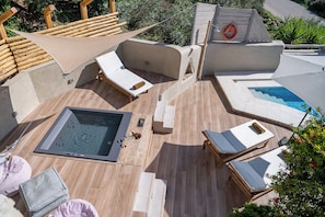 Eine Dachterrasse mit Whirlpool, Liegestühlen und einem kleinen Pool.