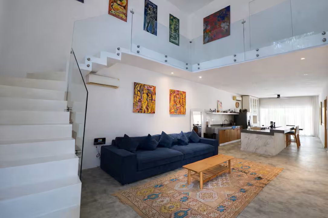 A spacious living area with a sofa, coffee table, and artwork on the walls.