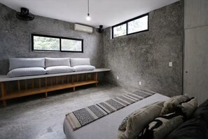 A modern bedroom with a built-in bench, a large bed, a patterned rug, and a view through a window. - Design Lovers’ Paradise /Boutique Home in Tulum (Tulum)