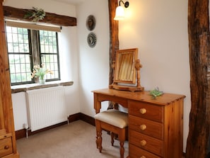 Ein Holztisch mit Spiegel, Heizkörper, Fenster mit Ausblick und einer Wandleuchte.