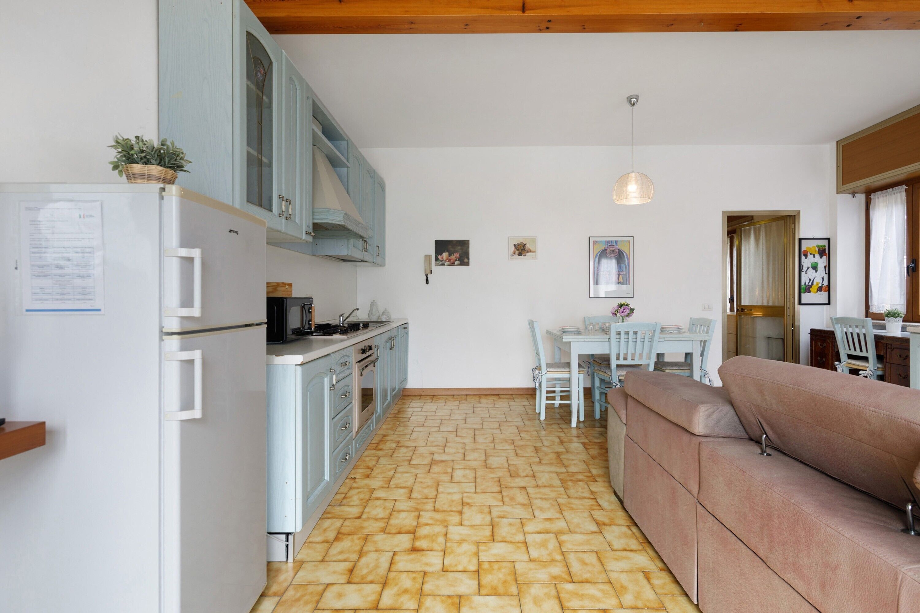 Une cuisine équipée d’un réfrigérateur, d’une cuisinière et de placards. On y trouve une table à manger avec des chaises et un canapé.