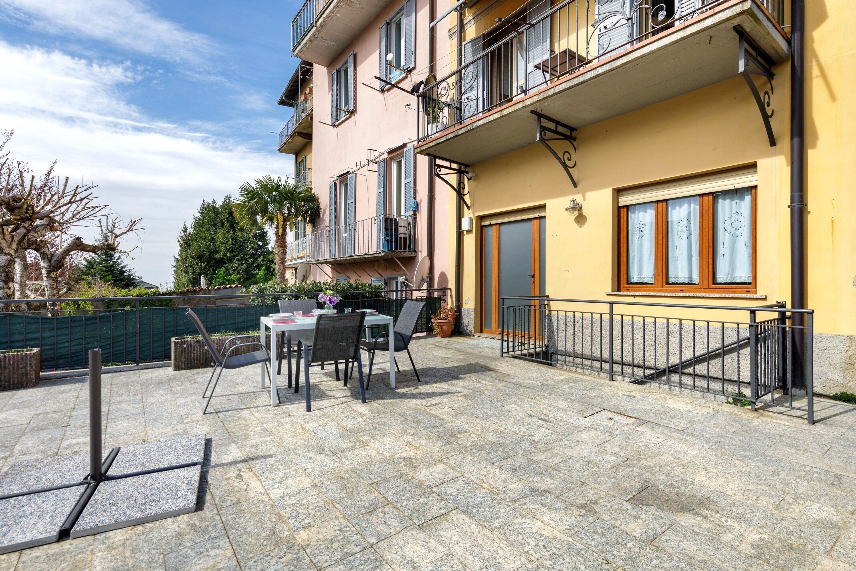 A building with a balcony, outdoor seating, and a stone patio.