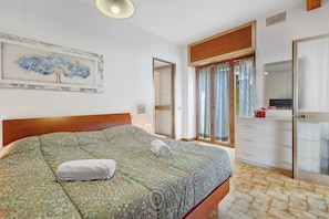 Una camera da letto con un letto, una cassettiera, uno specchio e un quadro appeso al muro.