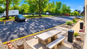 A parking lot with a picnic table and trash bins, surrounded by trees and a fence. - Hotel Blu (Columbia)