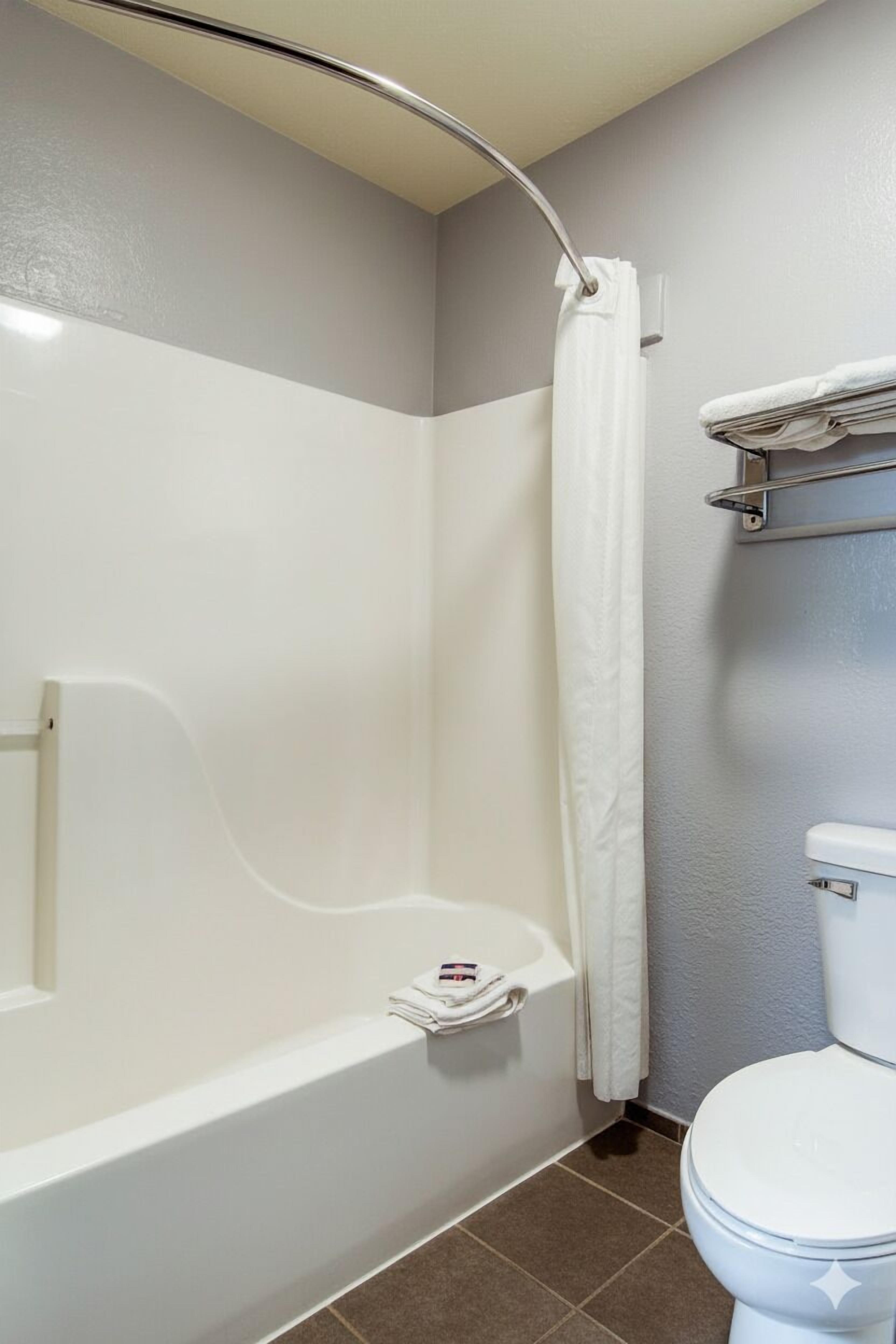 Bañera con ducha, toallas, papel higiénico
