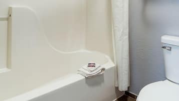 Bañera con ducha, toallas, papel higiénico