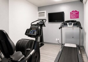 A fitness room with exercise equipment, a television, and a sign with exercise room rules. - Hotel Blu (Columbia)