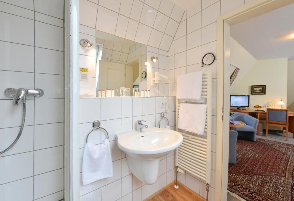Une salle de bain équipée d’un lavabo, d’un miroir, d’un porte-serviettes et d’une douche.