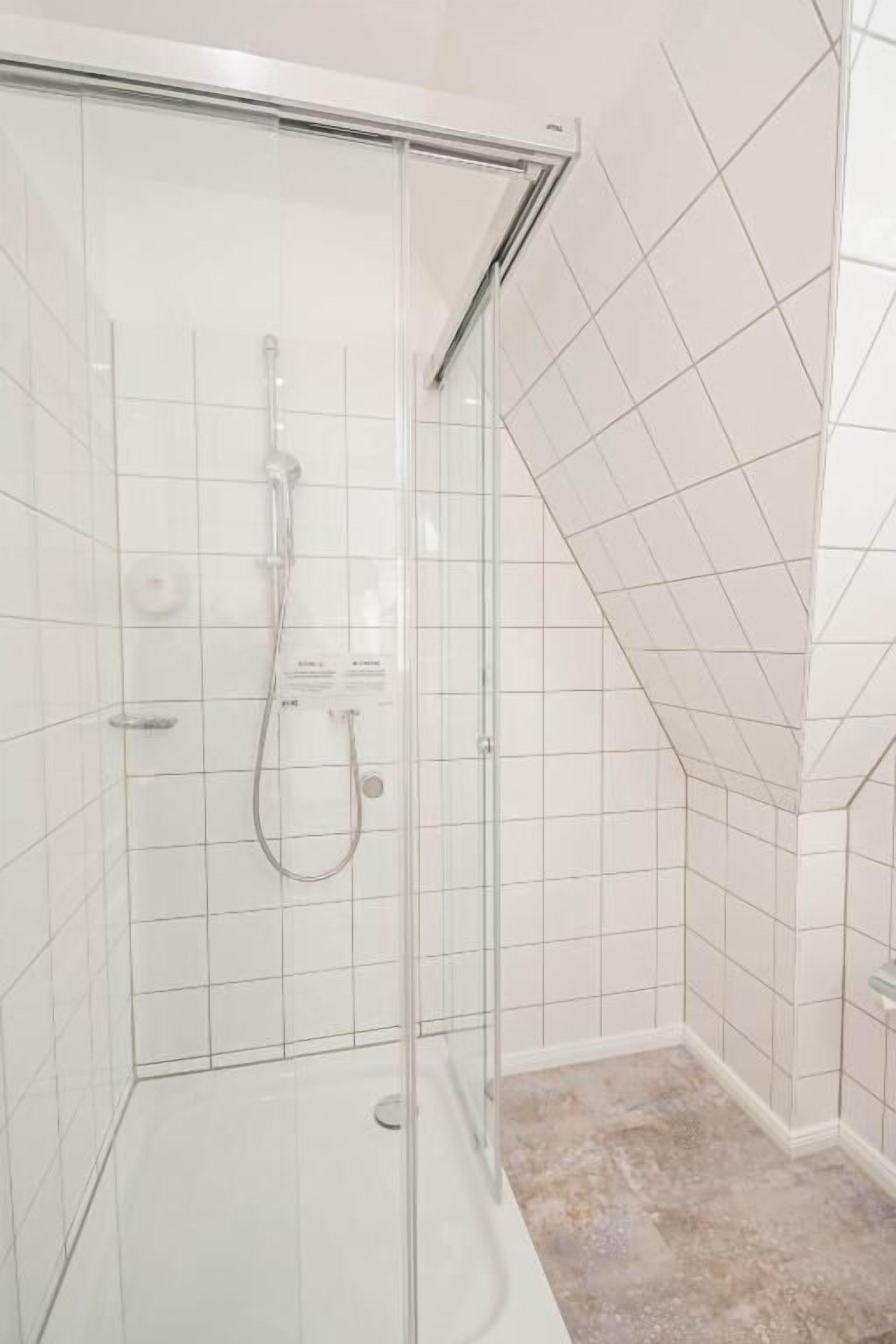 Eine Duschkabine mit Handbrause und einer fest installierten Bedienkonsole.