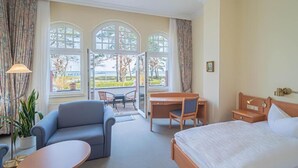 Een hotelkamer met een bed, een bureau, een stoel, een bank en grote ramen met uitzicht.