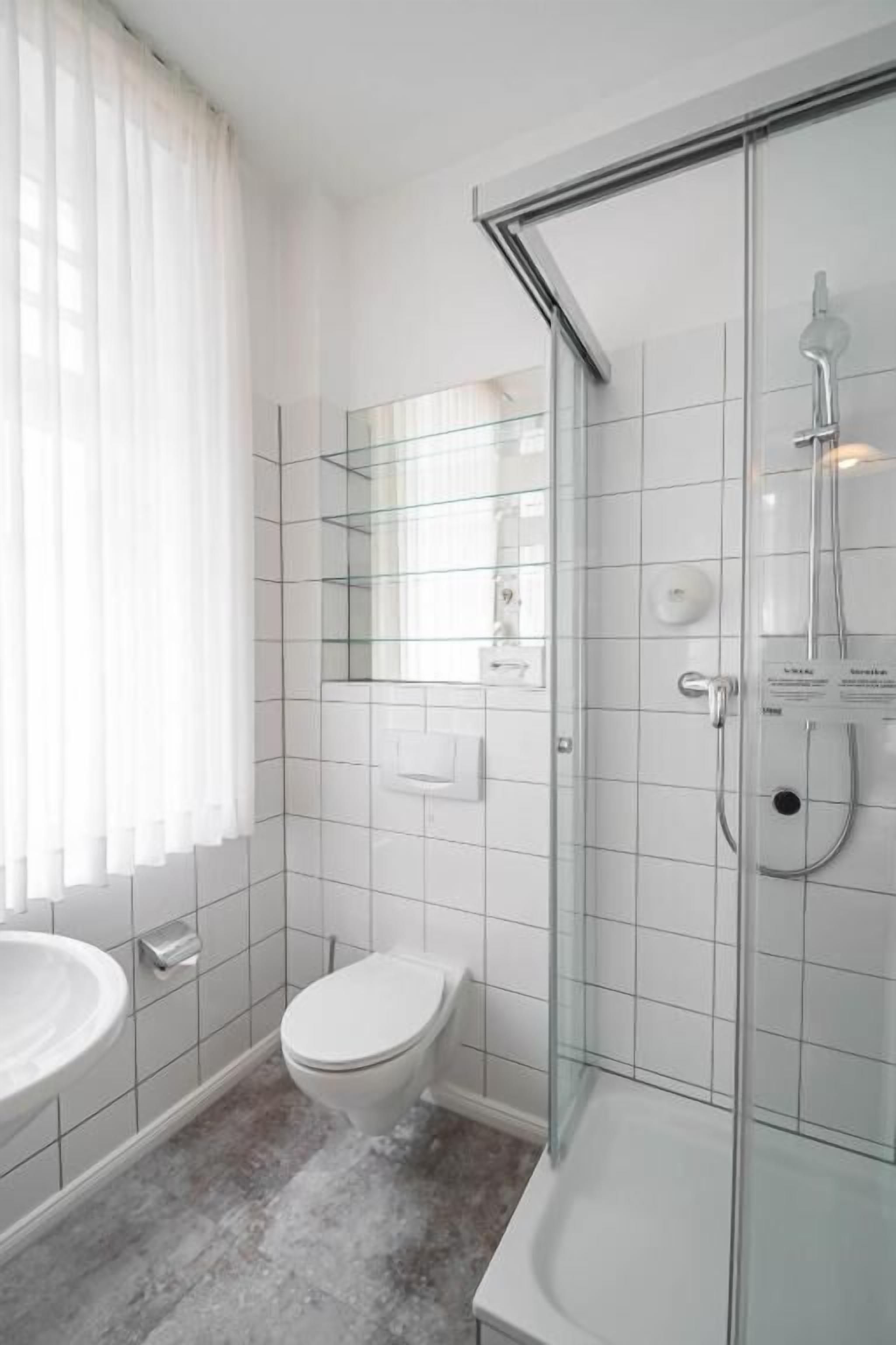 Une salle de bain moderne avec une douche à parois de verre, des toilettes et un lavabo.