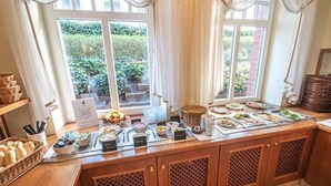 Een buffetopstelling met diverse gerechten en uitzicht op groen buiten.