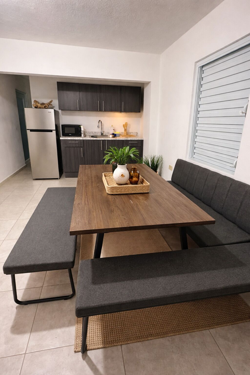 A modern kitchen with dark cabinets, a stainless steel refrigerator, and a microwave.