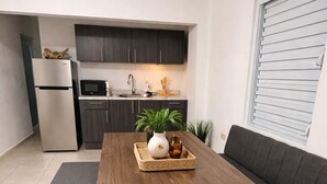 Cozinha moderna com armários escuros, geladeira de aço inoxidável e micro-ondas.