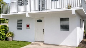 Um edifício branco de dois andares com varanda, porta e uma pequena janela.