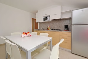 A modern kitchen with white cabinets, a stainless steel refrigerator, a microwave, and a gas stove. - Chic Retreat With Pool and Balcony (Lignano Sabbiadoro)