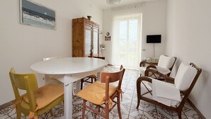 Un comedor con una mesa redonda, sillas, un armario y un televisor.