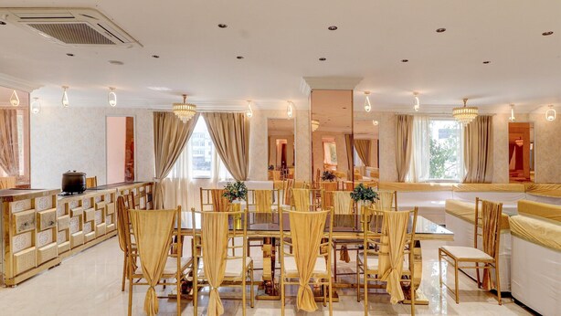 A spacious hotel dining area with a long table, chairs, and a bar area.