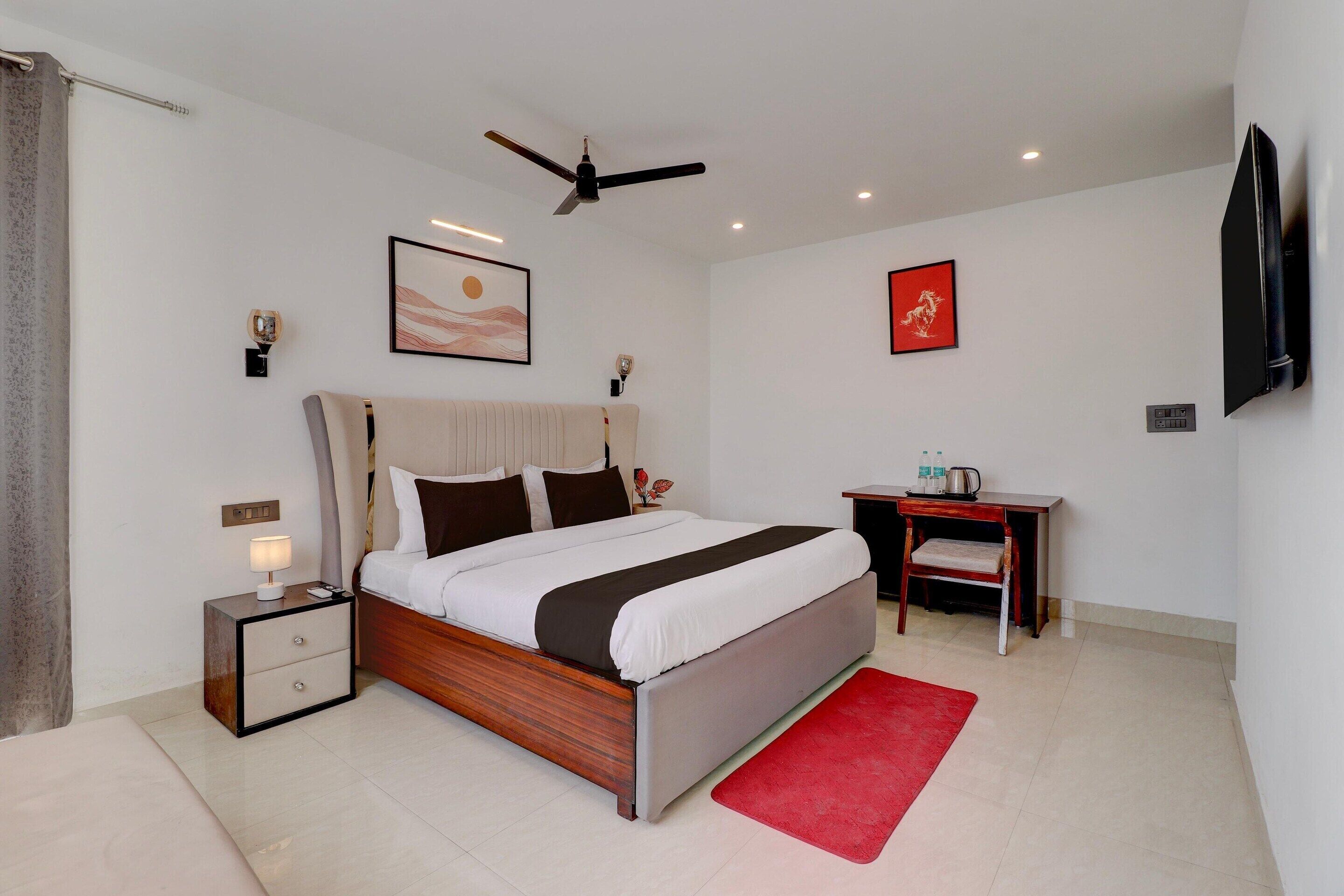 Ein modernes Schlafzimmer mit Bett, Nachttisch, Schreibtisch, Stuhl und Kunstwerken an den Wänden.