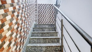 A staircase with a patterned wall on one side and a metal railing on the other.
