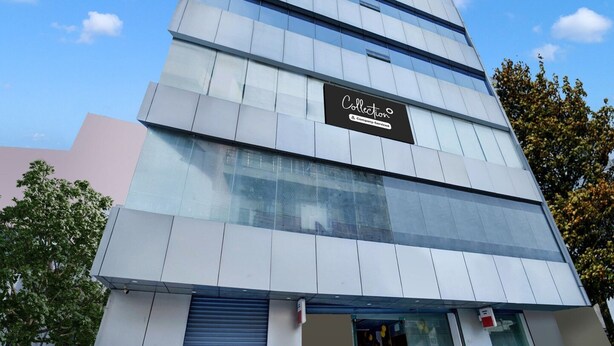 A multi-story building with a modern architectural design, featuring a prominent sign with the word 'Collection' and a company service logo.