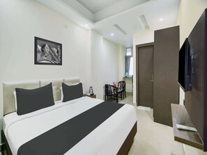 Une chambre d’hôtel avec un lit, un bureau, une chaise, une télévision et une porte.