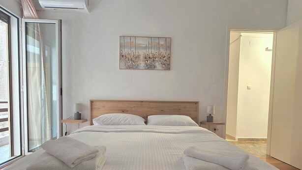 Ein Schlafzimmer mit Bett, Nachttisch, Wandklimaanlage, einem Gemälde und einer Schiebetür.