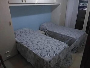 A small room with two single beds, a blue wall, and a white cabinet above the beds. - Three bedroom apartment in beautiful seaside Italian village (Marina di Ginosa)