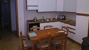 Una cocina funcional con armarios blancos, una mesa de comedor de madera y un colgador de luz.
