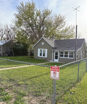 A residential property with a fenced yard, a private driveway sign, and a house with a chimney.