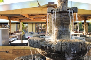 A stone fountain with water flowing from its top, surrounded by a wooden structure.