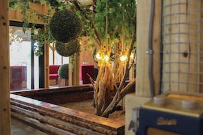 A wooden interior with a tree, a bench, and a table with a light fixture.