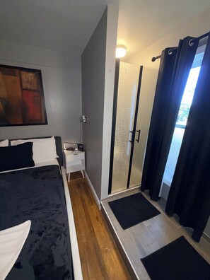 Ein modernes Schlafzimmer mit Bett, Nachttisch und einer Duschkabine mit Glastüren.