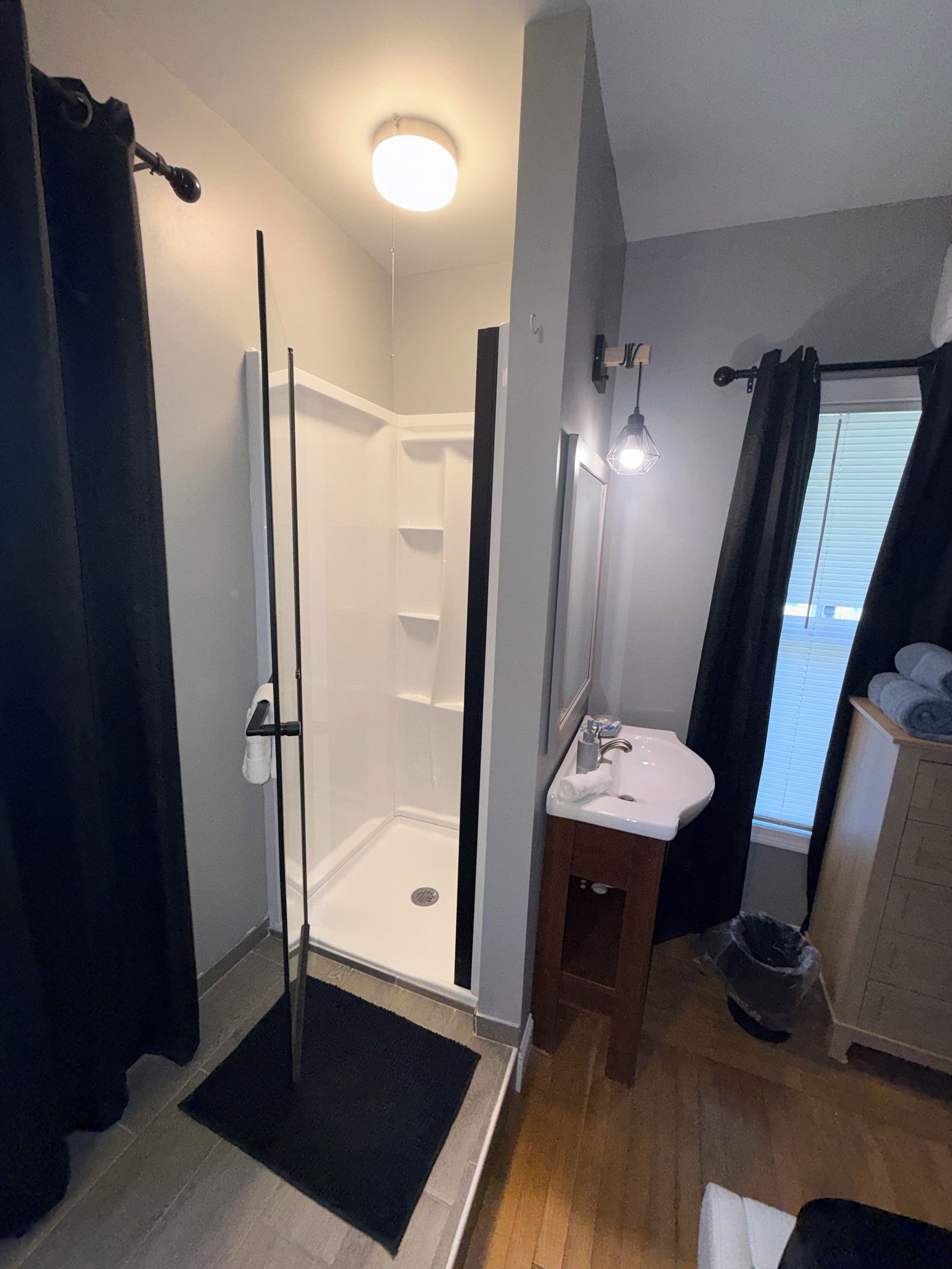 A bathroom with a shower, sink, and a towel rack.