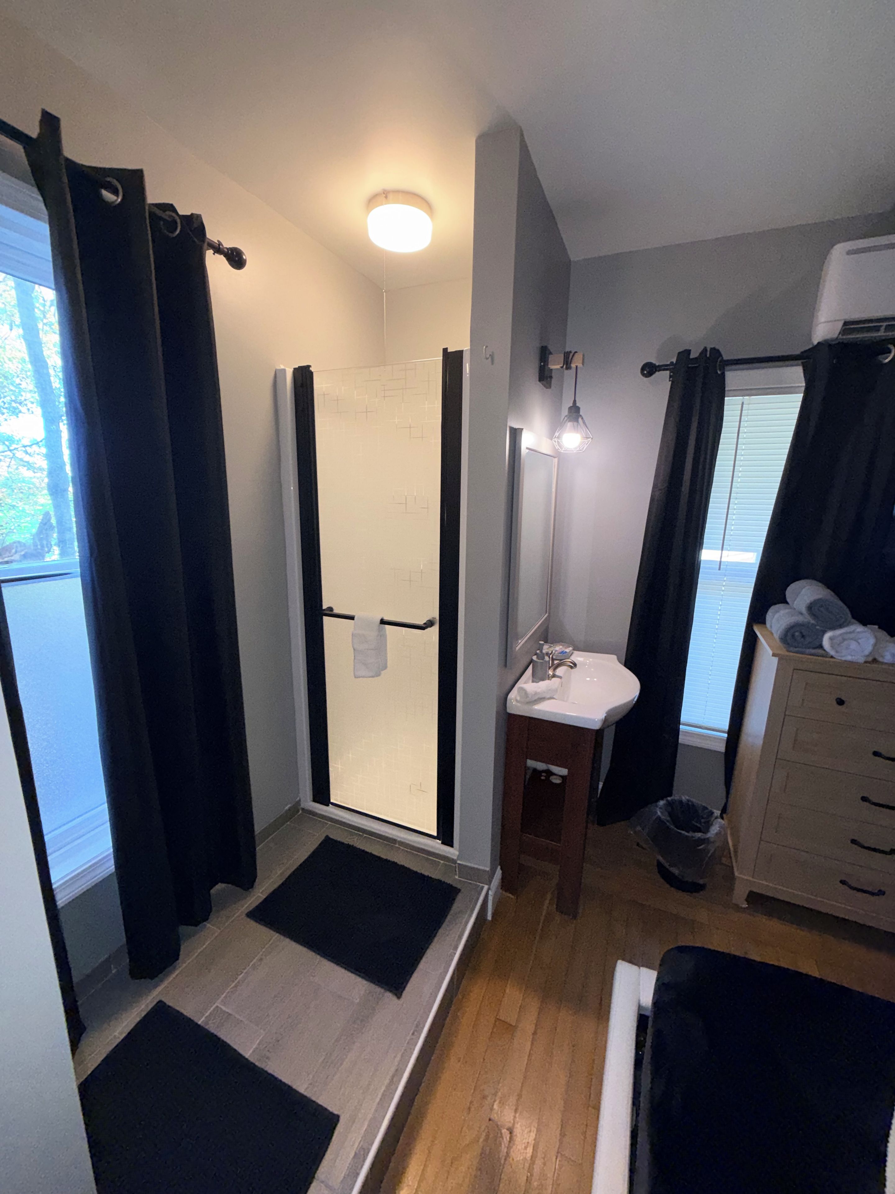 A bathroom with a shower, sink, and wooden cabinet.