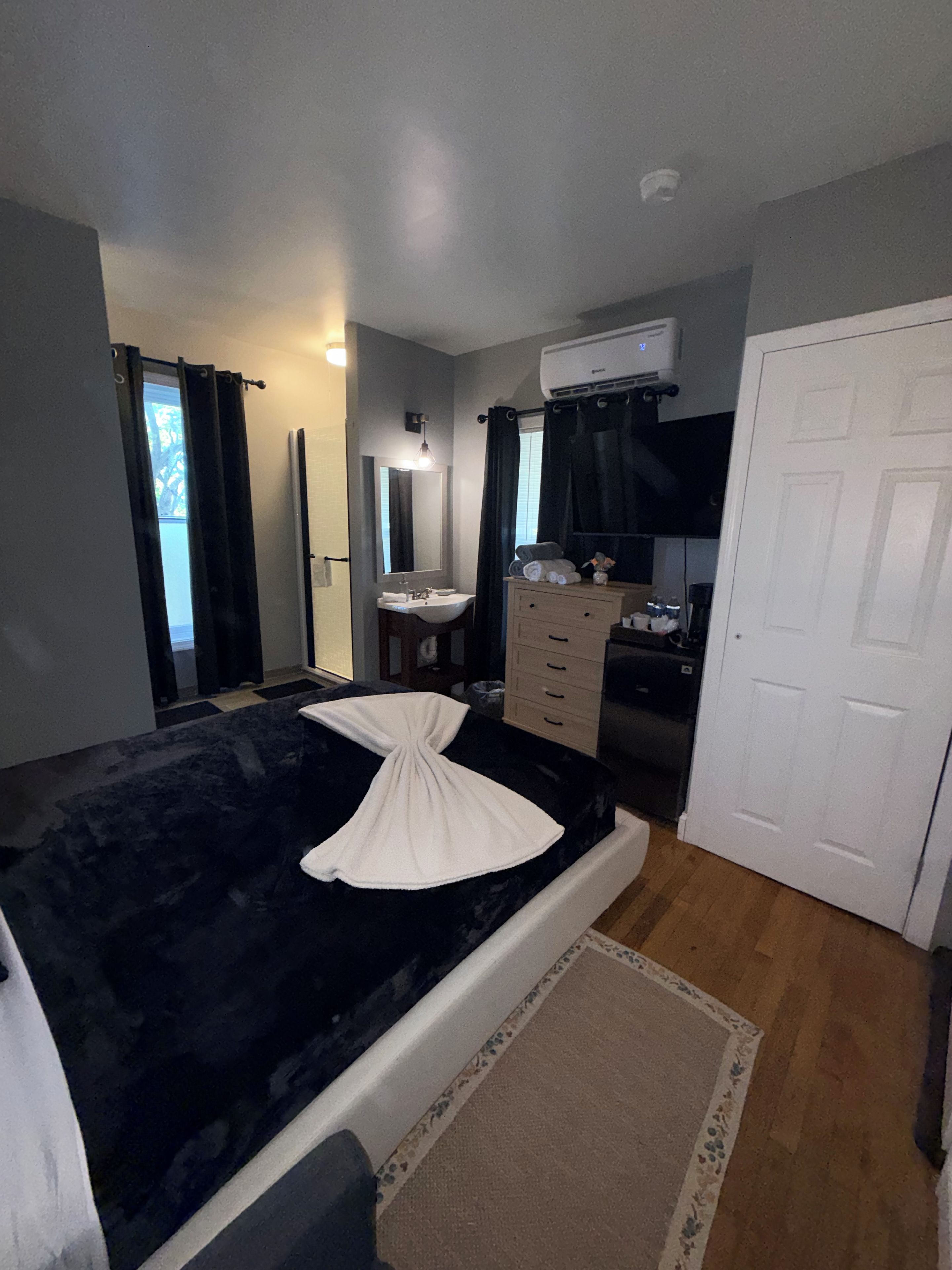A bedroom with a bed, a dresser, a mirror, a sink, and a door.