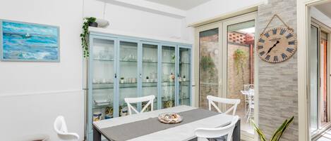 A dining area with a table, chairs, a clock, and a glass cabinet.