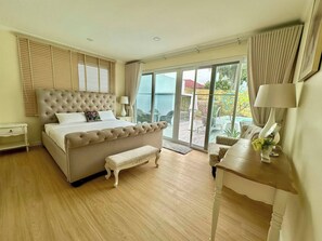 Ein Schlafzimmer mit einem großen Bett, einer Sitzbank, einem Schreibtisch und Blick ins Freie durch eine Schiebetür.