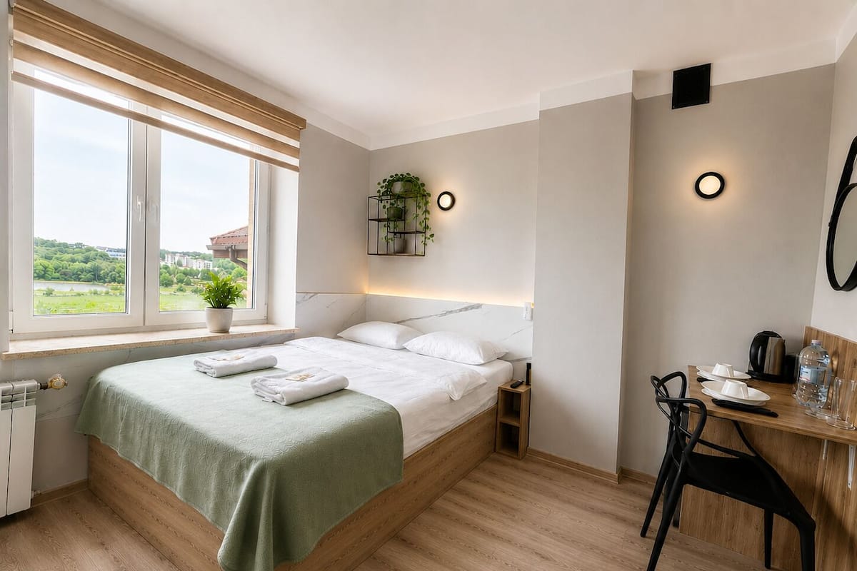 Camera da letto con un letto, un comodino, una sedia, una scrivania, una pianta in vaso e una finestra con vista.