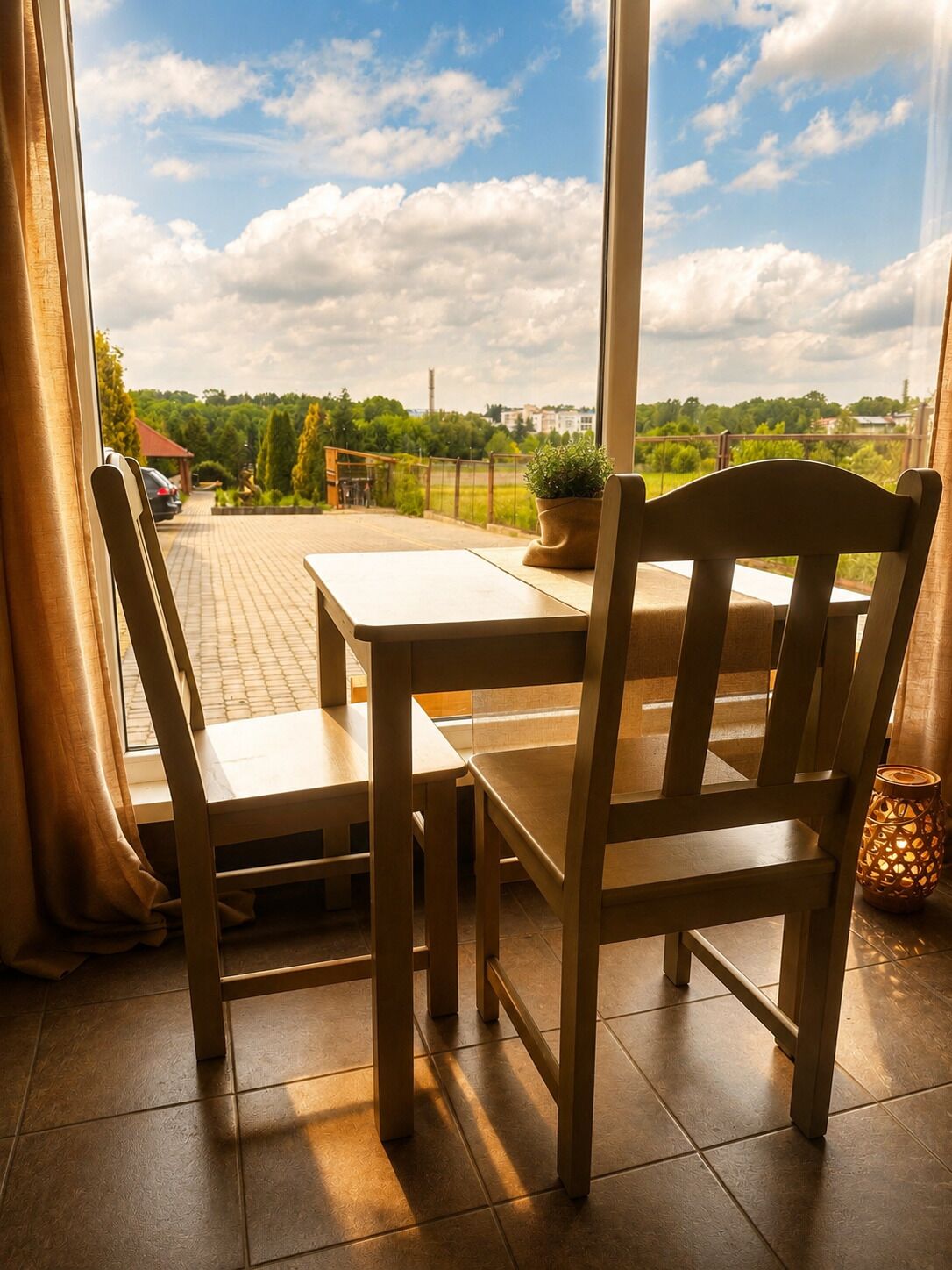 Mesa y sillas de madera en un balcón con vistas a zonas verdes y edificios.