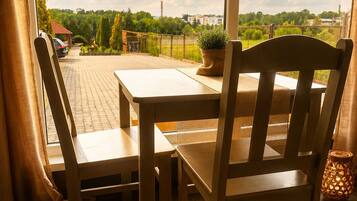 Mesa y sillas de madera en un balcón con vistas a zonas verdes y edificios.