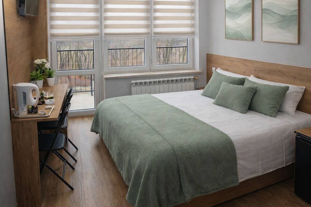 Una camera da letto con un letto, una scrivania con sedia, un termosifone e una finestra con persiane.