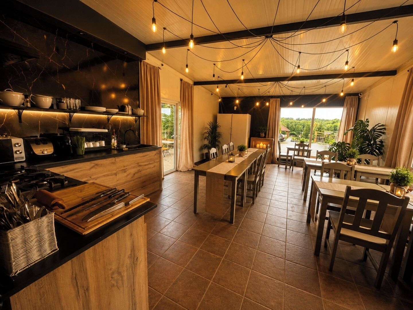 A spacious kitchen with a central island, a dining area with wooden furniture, and a view of greenery outside.