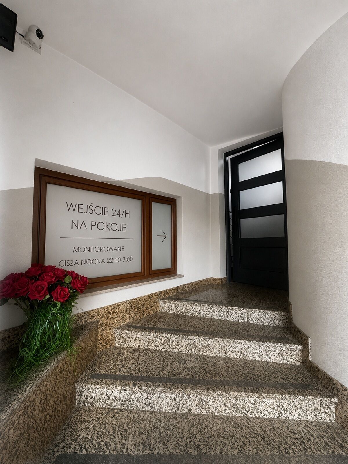 A staircase leading to a room with a sign indicating 24-hour access and a monitor room available from 22:00 to 7:00.
